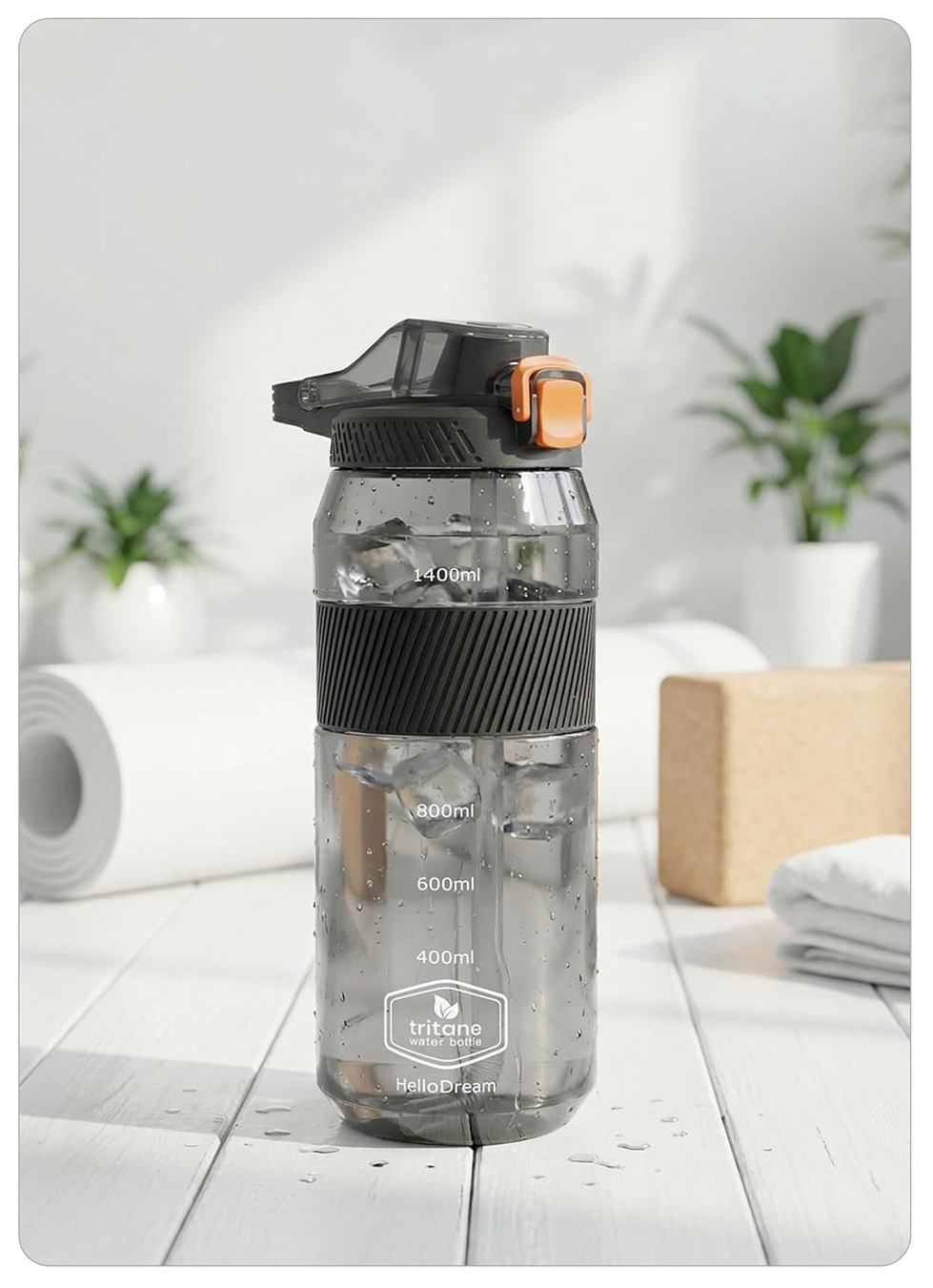 A translucent gray Tritane water bottle with a black flip-top lid and orange accent, standing on a white wooden surface with a softly blurred home background.