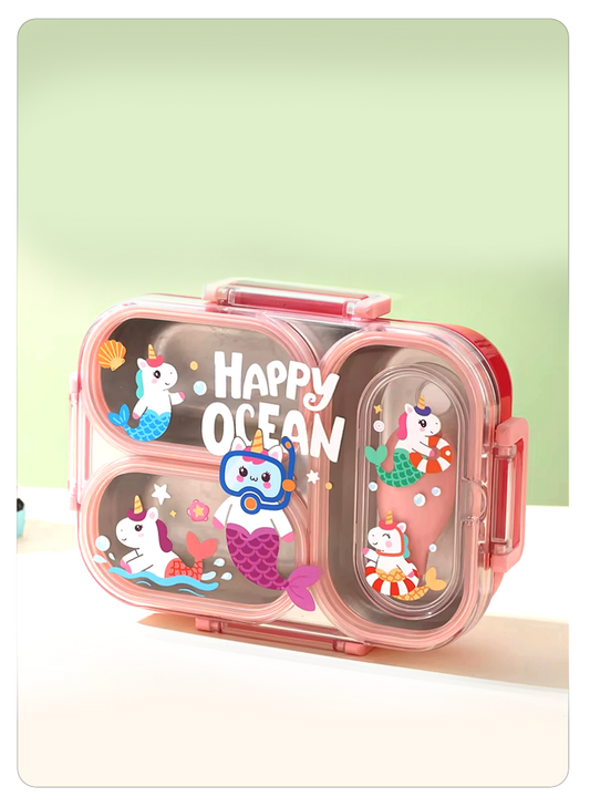 A pink compartment lunch box with clear plastic panels decorated with cartoon mermaids, sea creatures, and the words 'Happy Ocean,' shown on a clean pale green and white background.